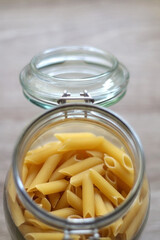 Glass jar with pasta in the kitchen. Selective focus.