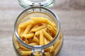 Glass jar with pasta in the kitchen. Selective focus.