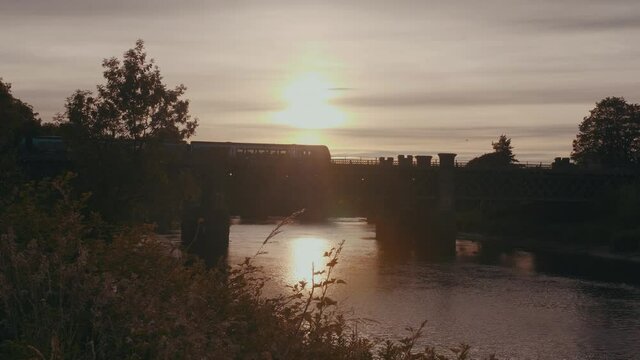 Static shot of a tram crossing the bridge over River Forth at golden hour in Stirling, UK