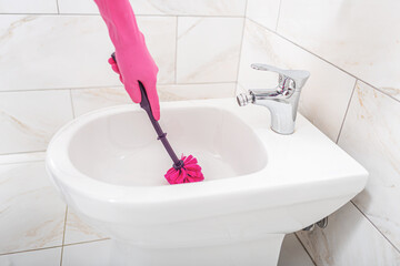 A woman cleans a toilet.