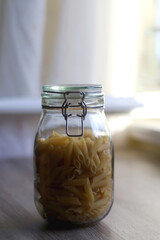 Glass jar with pasta in the kitchen. Selective focus.