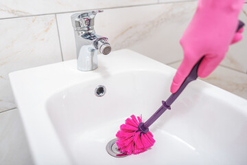 A woman cleans a toilet.