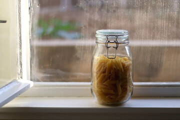 Glass jar with pasta in the kitchen. Selective focus.