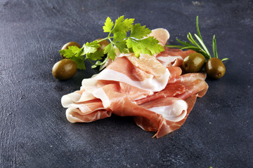 Italian prosciutto crudo or jamon with rosemary. Raw ham appetizer on table