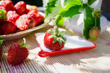 Freshly cut strawberries on a wooden cutting board and delicious strawberries in a glass bowl on wooden table. Season's fruit. Healthy food. Wooden background. Ecological and organic food. Agriculture