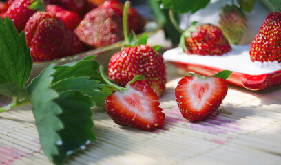 Freshly cut strawberries on a wooden cutting board and delicious strawberries in a glass bowl on wooden table. Season's fruit. Healthy food. Wooden background. Ecological and organic food. Agriculture
