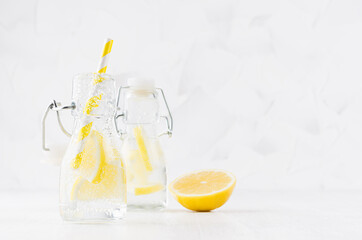 Cold fresh fruit citrus beverages of yellow lemon with soda water, bubbles, funny striped straw on simple soft bright white background, copy space.