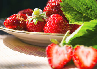 Freshly cut strawberries on a wooden cutting board and delicious strawberries in a glass bowl on wooden table. Season's fruit. Healthy food. Wooden background. Ecological and organic food. Agriculture