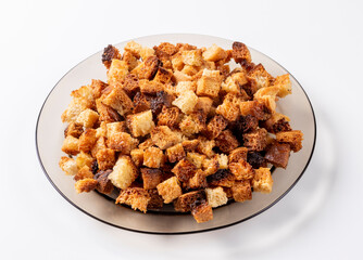 Small pieces of bread fried in oil lying on a transparent brown plate on a light background. Fried crackers.
