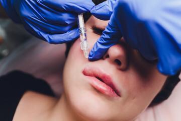 Young woman receiving a injection in her lips, close up.