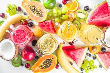 Assorted different fruit smoothies and juices with tropical fresh fruits and berries. Clean eating, healthy lifestyle, diet and vitamin drink beverages concept. Top view flatlay