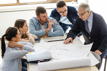 College professor examining blueprint with group of his students.	
