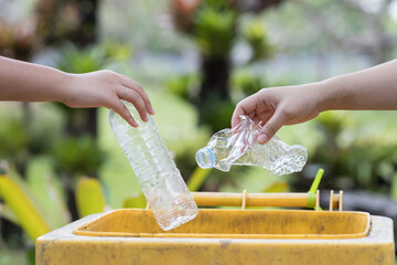 Hand a man and girl throwing empty plastic bottle into the trash Recycling Concept.
