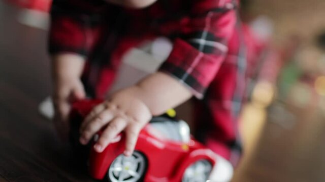 A child in red pajamas is playing with a toy car.