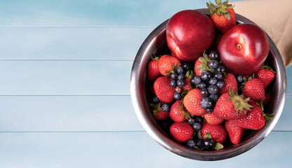 Juicy and fresh organic berries in a bowl  on a blue wood background.
Concept for healthy nutrition.
Close up view.
Copy space. Tropical fruit  background.