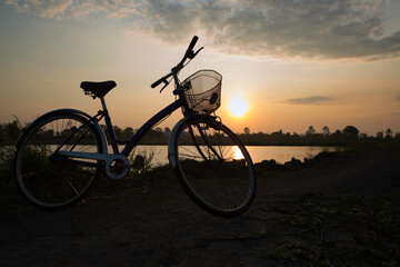 Plakat Silhouette Bicycle parking with sunset or sunrise background. It was parking nearby the pond for relaxing