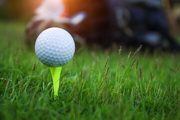 Golf ball on tee ready to be shot. golf ball on tee in the evening golf course with sunshine.