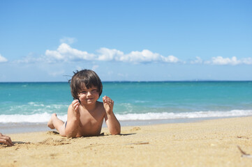 Fototapeta na wymiar Child playing in sand on the beach. Cheerful boy play on send on summer holiday