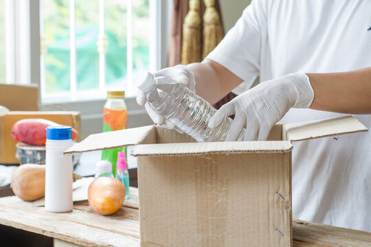 Hand Of Volunteer Wear Sanitary Gloves Packing Food Or Product For Delivery Service People Who Get Impact By Coronavirus, Covid-19. Social Distancing Concept.