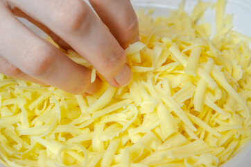 woman's hand takes a large grated cheese from a plate with her fingers.