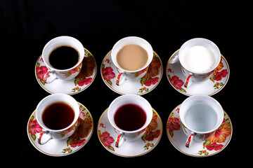 Six cups and saucers filled with water, juice, tea, coffee, milk and coffee with milk on a dark fabric background © Aleksey