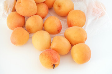 Apricots rolling out of a plastic bag.