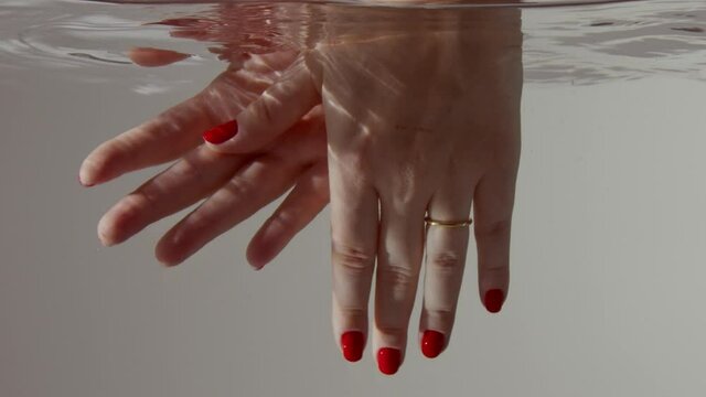 female hands submerged into the clear water underwater side view