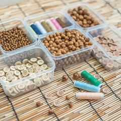 Wooden Beads and Buttons, Natural Craft Supplies, Colorful Sewing Thread on Bamboo Background