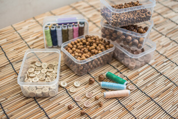 Obraz na płótnie Canvas Wooden Beads and Buttons, Natural Craft Supplies, Colorful Sewing Thread on Bamboo Background