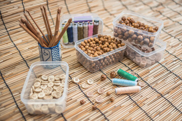 Fototapeta premium Wooden Beads and Buttons, Natural Craft Supplies, Colorful Sewing Thread on Bamboo Background