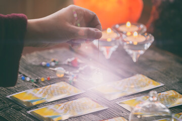 Hand with pendulum over tarot cards