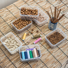 Wooden Beads and Buttons, Natural Craft Supplies, Colorful Sewing Thread on Bamboo Background