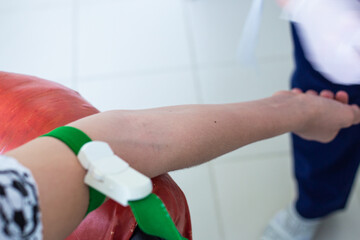 the patient hand is tightened with a medical tourniquet, the nurse is preparing for blood sampling...