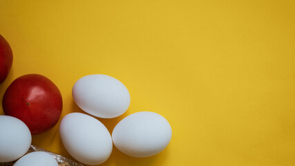 Raw eggs and tomatoes on a yellow background close up