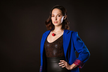 A business woman in a blue jacket poses for the camera on a dark background