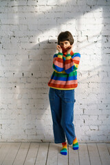 Portrait of a young woman in a multicolored sweater, covering her face with a sweater . The concept of shyness