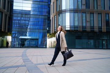 Fototapeta na wymiar Business woman in a coat and suit goes near the business