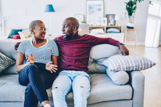 Young african american marriage having discussion about problem sitting at couch in living room, romantic couple talking about relationship looking at each other spending time together