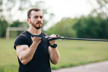 Attractive Man Exercising With A Resistance Band on nature As Pa