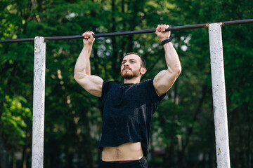 Fototapeta premium strong athlete doing pull-up on horizontal bar in park. Man Doin