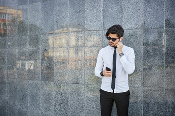 Obraz premium Handsome businessman making a phone call or using a phone outside