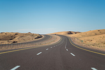Empty desert highway surrounded by sand dunes