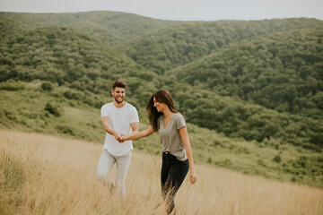 Naklejka premium Happy young couple in love walking through grass field