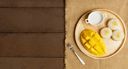 Top view Yellow half  mango with small fork. Mango fruit cubes on the wooden table. Tropical fruit asia. Fresh yellow mango peel and Sliced cubes on wood butcher. Dessert fruit.