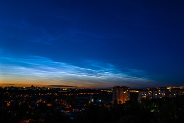 Noctilucent clouds during night time, city scape. Highest clouds in the Earth's atmosphere, beautiful sky phenomenon.