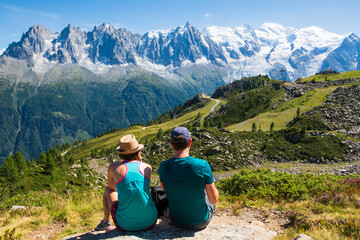 French Alps summer travel. Couple (unidentified people, back view) of hikers admiring beautiful...