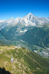 Cable car cabin transportation from Chamonix to Le Brevent balcony. Beautiful view of Mont Blanc mountains range and Chamonix town in green valley. Summer vacation in Alps, Savoie, France.