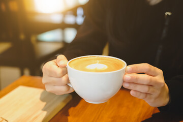 Young woman holding coffee cup inside cafe shop.