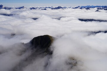 Green mountain peak surrounded by clouds - more peaks in far - Fjordland National Park - Doubtful Sound.jpeg