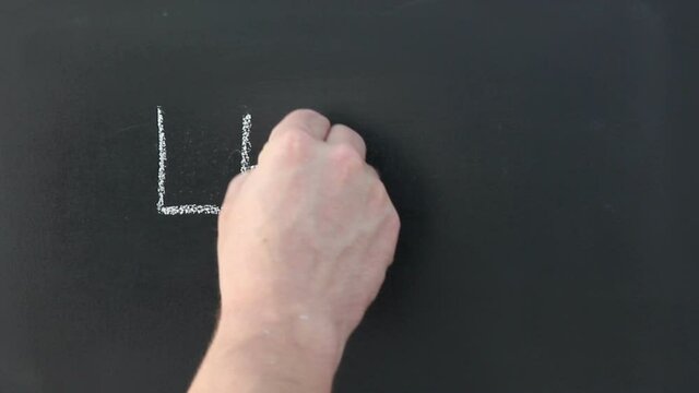 Writing the words 'Learn' on a Chalkboard - The person is using chalk to write with their hand this text. Stock Video Clip Footage